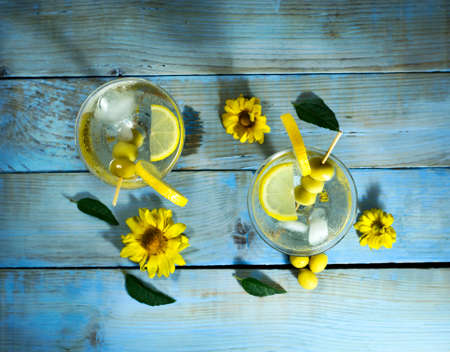 Martini with olives, lemon and ice on the old blue wooden tableの写真素材