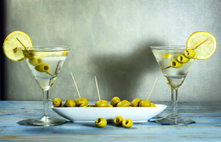 Martini with olives, lemon and ice on the old blue wooden tableの写真素材