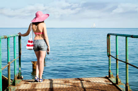 Young girl looking to the sea with a yacht hot summer dayの写真素材