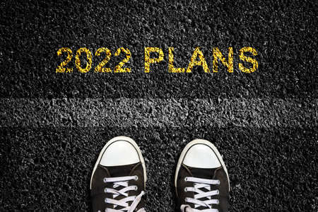 2022. Plans, on an asphalt road surface, and sneakers in front of the lane mark. Top view. The concept of the coming New Year, new plans, and ideas. Business, lifestyle.の写真素材