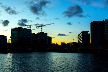Tower construction cranes and buildings at sunset. Construction and real estate Copenhagen. Denmark. Construction background.の写真素材