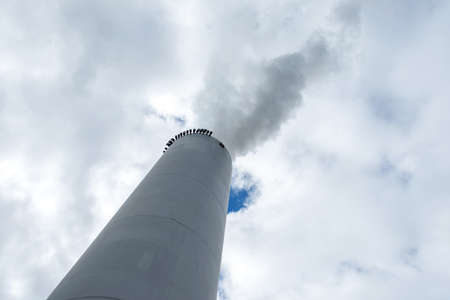 Chimney and smoke in the cloudy sky. Bottom view.Ecology. Environment protection.の写真素材
