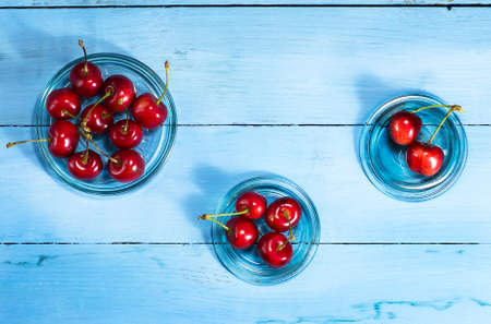 Cherries in glass saucers on a blue wooden background.Top viewの写真素材