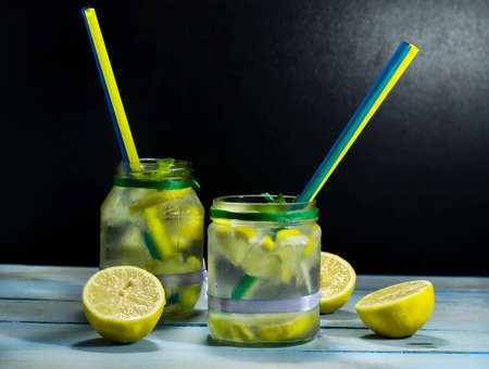 Cold lemonade in bottles with lemons on a black backgroundの写真素材