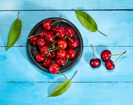 Cherries in saucers on a blue wooden background.Top viewの写真素材