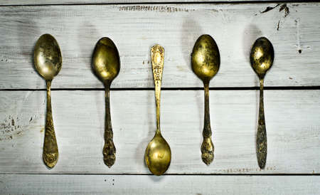 Five old spoons on a white wooden background. Top viewの写真素材