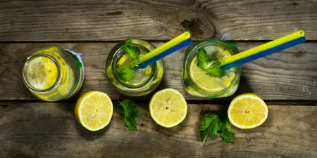 Cold lemonade in bottles with lemons on a wooden background. Top viewの写真素材