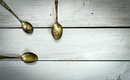 Three old spoons on a white wooden background. Top viewの写真素材