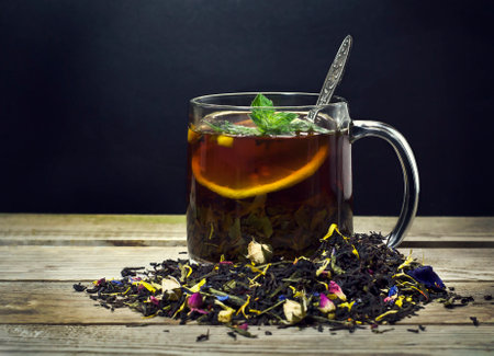 Cup of tea with lemon, mint and spoon on a wooden backgroundの写真素材