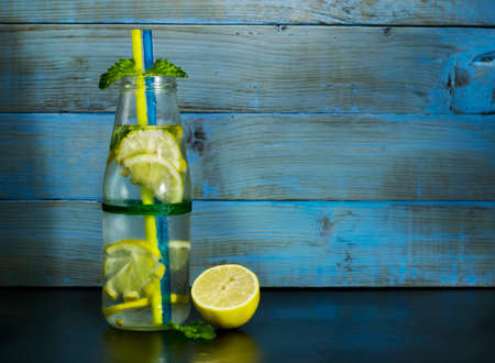 Cold lemonade in bottles with lemons on a blue wooden background.の写真素材