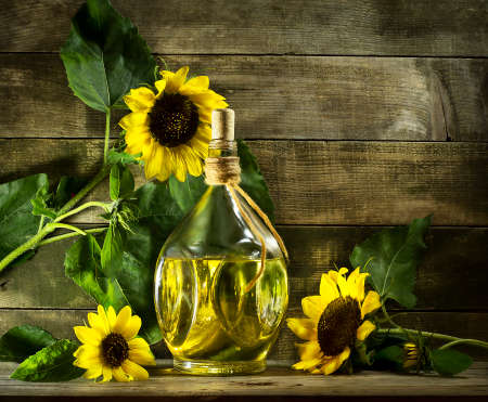 Sunflower oil in an old glass bottle. On the wooden background with sunflowersの写真素材