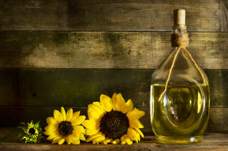 Sunflower oil in an old glass bottle. On the wooden background with sunflowersの写真素材