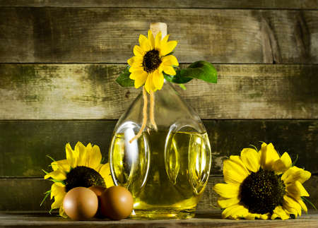 Sunflower oil in an old glass bottle with eggs. On the wooden background with sunflowersの写真素材