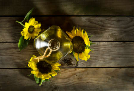 Sunflower oil in an old glass bottle. On the wooden background with sunflowers
