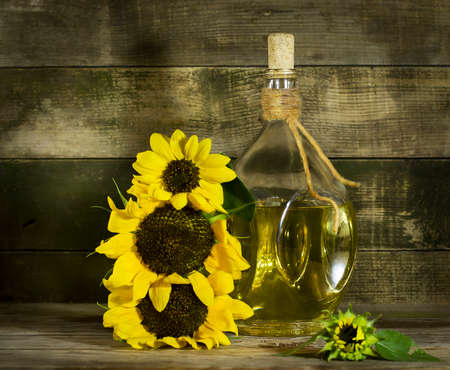 Sunflower oil in an old glass bottle. On the wooden background with sunflowersの写真素材
