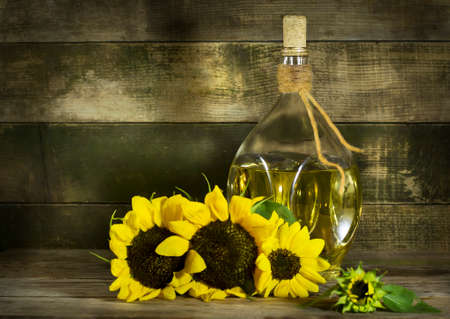 Sunflower oil in an old glass bottle. On the wooden background with sunflowersの写真素材