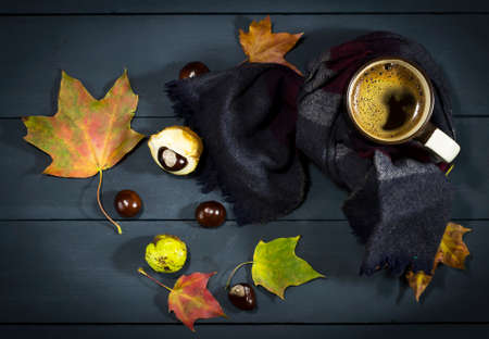 A cup of coffee with autumn leaves and chestnuts. On a blue wooden backgroundの写真素材