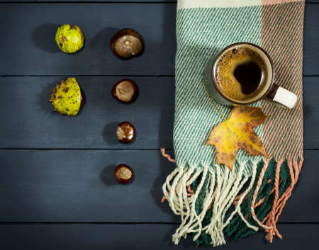 A cup of coffee with autumn leaves and chestnuts. On a blue wooden backgroundの写真素材