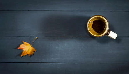 Cup of coffee on a blue wooden table with autumn leavesの写真素材