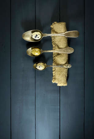 Quail eggs in old spoons. On a blue wooden backgroundの写真素材