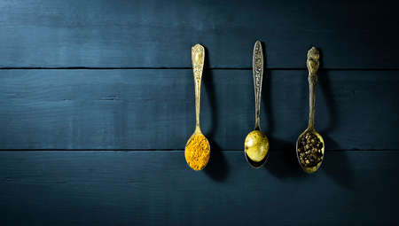 Quail egg in a spoon and spices. On a blue wooden backgroundの写真素材