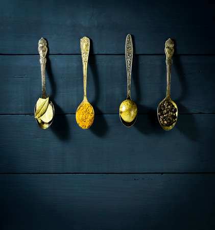 Quail egg in a spoon and spices. On a blue wooden backgroundの写真素材