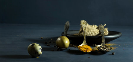 Quail egg in a spoon and spices. On a blue wooden backgroundの写真素材