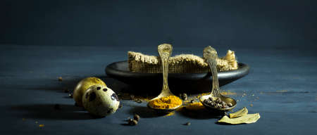 Quail egg in a spoon and spices. On a blue wooden backgroundの写真素材