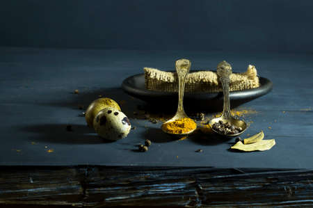 Quail egg in a spoon and spices. On a blue wooden backgroundの写真素材