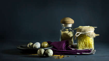 Spices and pasta in jars with quail eggs. On a blue wooden backgroundの写真素材