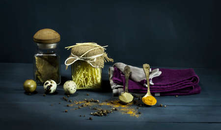 Spices and pasta in jars with quail eggs. On a blue wooden background