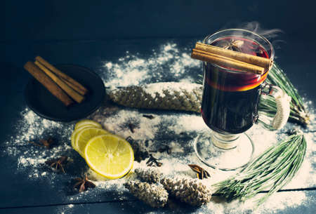 Glass of hot Mulled wine with sticks of cinnamon, anise and lemon on a blue wooden background. Winter, New Year, Christmas still life.の写真素材