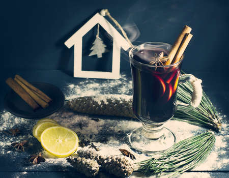 Glass of hot Mulled wine with sticks of cinnamon, anise and lemon on a blue wooden background. Winter, New Year, Christmas still life.の写真素材