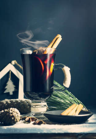 Glass of hot Mulled wine with sticks of cinnamon, anise and lemon on a blue wooden background. Winter, New Year, Christmas still life.の写真素材