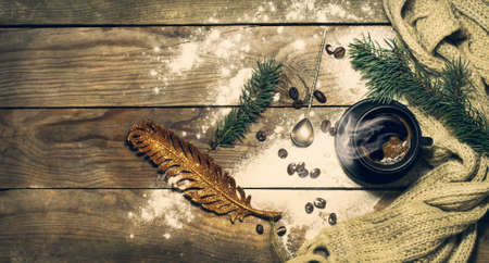 Cup of coffee with beans, a warm scarf with pine branches. Winter, New Year, Christmas still life. Wooden backgroundの写真素材