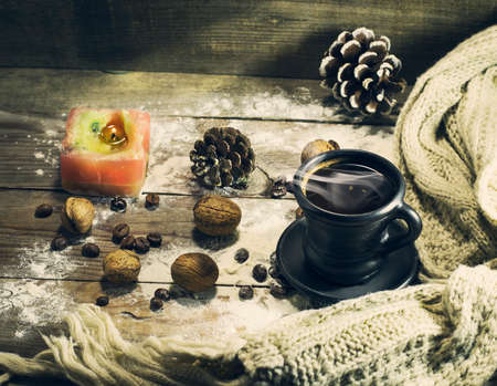 A cup of coffee with grains, nuts, warm scarf, with pine branches. Winter, New Year, Christmas still life. Wooden backgroundの写真素材