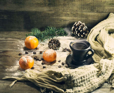 Cup of coffee with beans, mandarin, warm scarf, with pine branches. Winter, New Year, Christmas still life. Wooden backgroundの写真素材