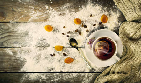 Cup of tea with lemon, dried apricots, raisins, warm scarf, with pine branches. Winter, New Year, Christmas still life. Wooden backgroundの写真素材
