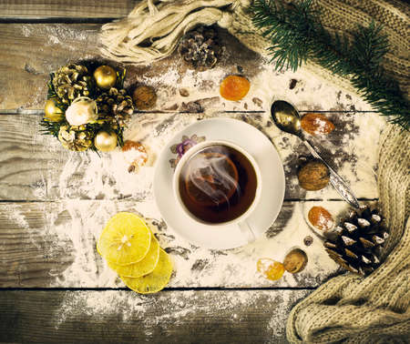 Cup of tea with lemon, dried apricots, raisins, warm scarf, with pine branches. Winter, New Year, Christmas still life. Wooden backgroundの写真素材