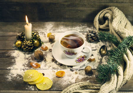 Cup of tea with lemon, dried apricots, raisins, warm scarf, with pine branches. Winter, New Year, Christmas still life. Wooden backgroundの写真素材