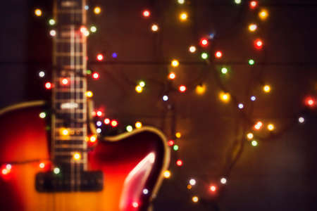 Old electric guitar with a lighted garland on a dark wooden background. Out of focus background....