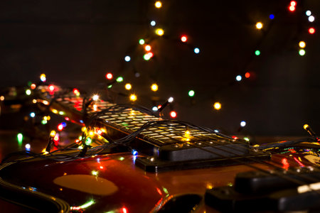 Old electric guitar with a lighted garland on a dark wooden background. Greeting, Christmas, New Year greeting card. Copy space.の写真素材