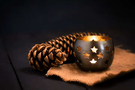 Christmas New Year composition with a candle and fir cones on a dark background. Greeting card. Christmas, New Year background with copy space.の写真素材