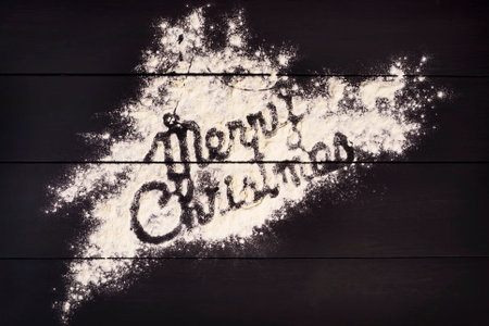 The inscription Merry Christmas, written with flour on a dark wooden background. Christmas greeting card. Celebratory background.の写真素材