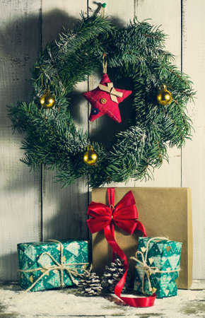 Christmas wreath with ornaments and gifts on the old wooden backgroundの写真素材