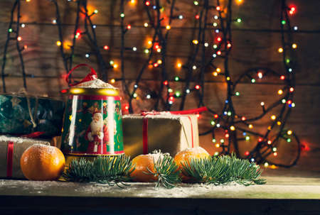 New year composition with tangerines and gifts on the old wooden background with Christmas tree garlandの写真素材