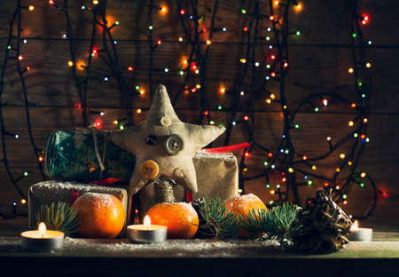New year composition with tangerines and gifts on the old wooden background with Christmas tree garlandの写真素材