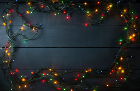 Glowing Christmas tree garland in the form of a frame on a blue wooden backgroundの写真素材