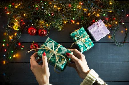 Hands girl with Christmas present and pine branches on a blue wooden backgroundの写真素材