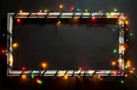 Glowing Christmas tree garland on old frame. On a blue wooden background.の写真素材